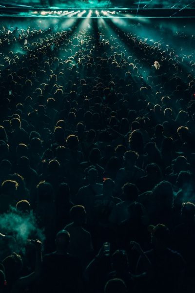 Energetic crowd enjoying a night concert with dramatic lighting effects, creating a lively atmosphere.
